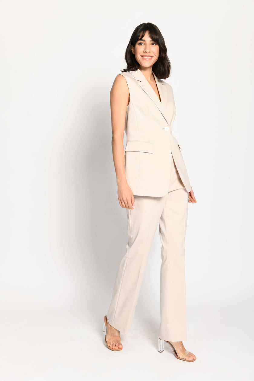 Taillierter ärmelloser Blazer in der Farbe Beige mit Reverskragen und Pattentaschen – gehende Pose, Blick nach vorne