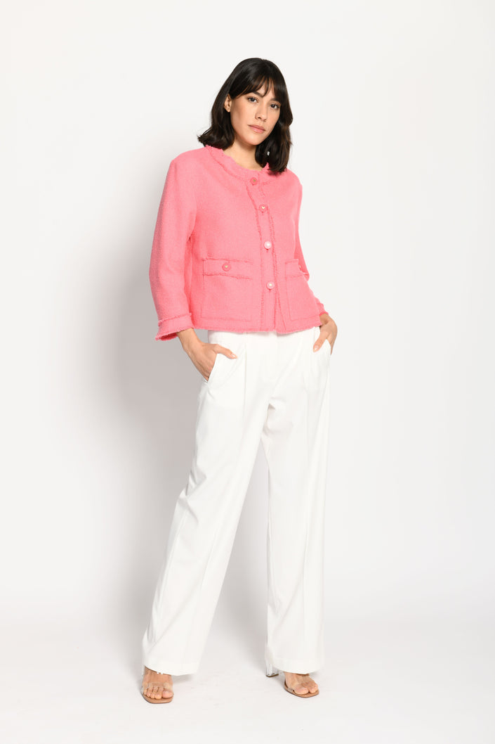 Model trägt langärmelige rosa-farbige Kastenjacke mit Fransen und Schmetterlingsknöpfen – stehende Pose, Blick nach vorne