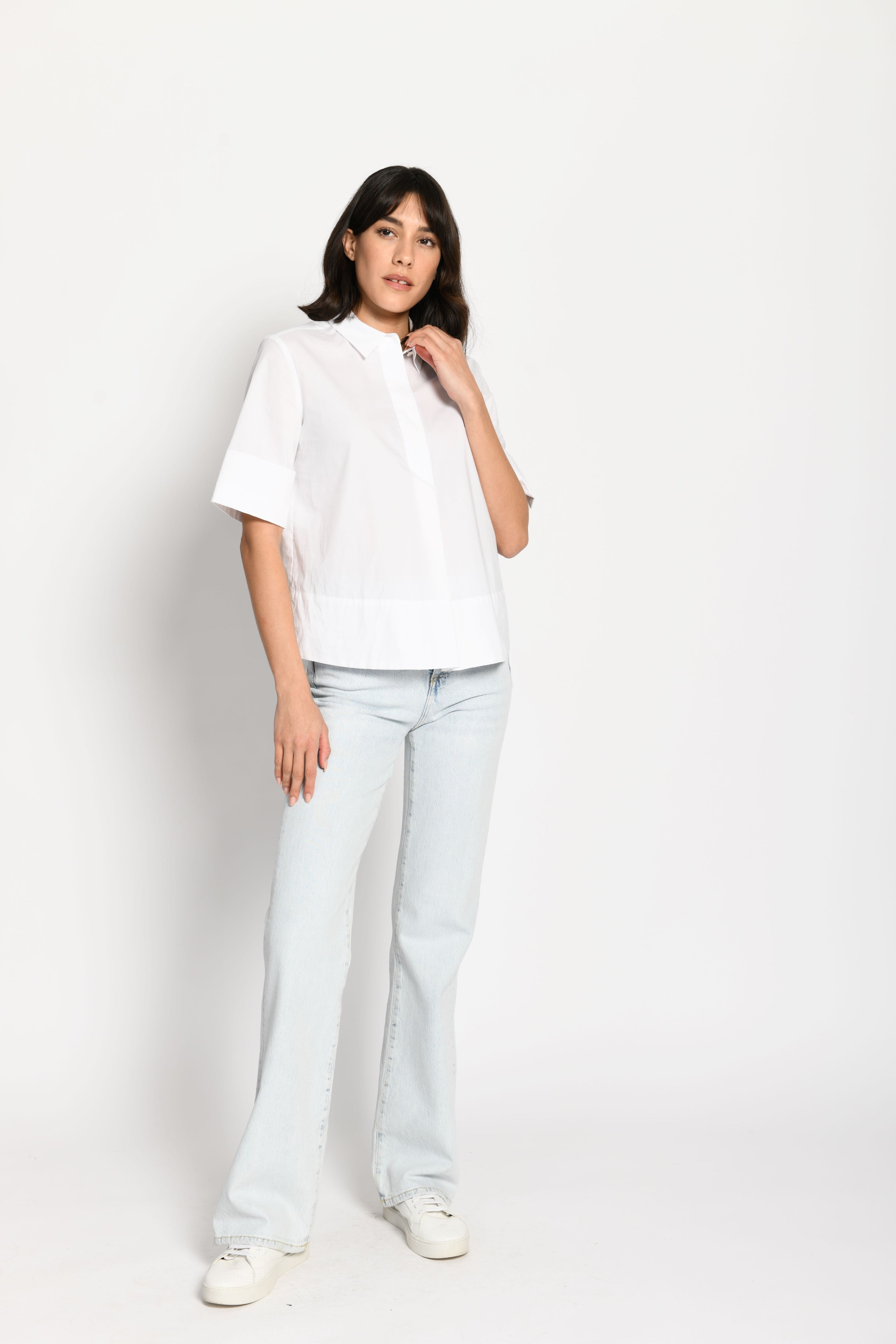 Model trägt kurze kastige Boxy-Bluse in der Farbe Weiß mit kurzen Ärmeln, passend zu einer Jeans – Vorderansicht