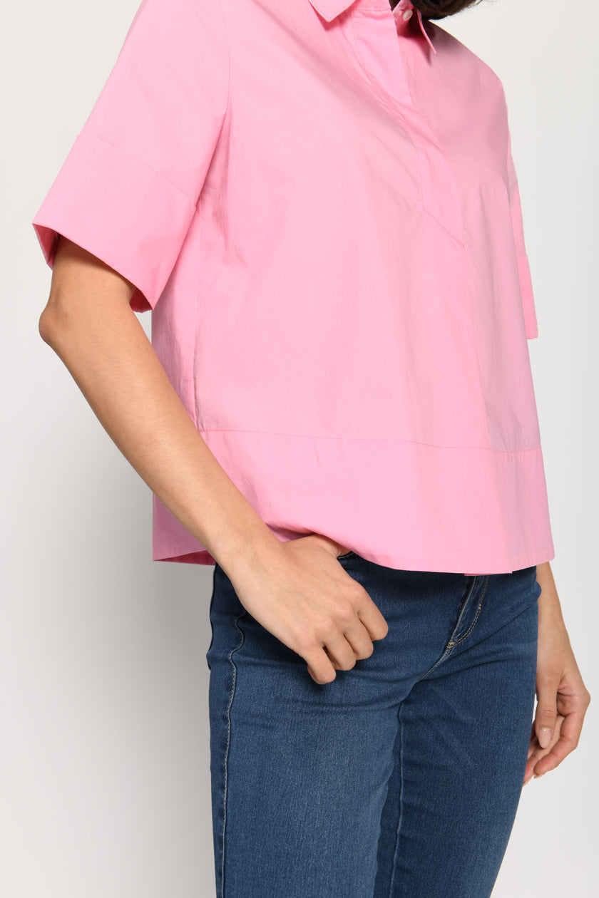 Model trägt kurze kastige Boxy-Bluse in der Farbe Pink mit kurzen Ärmeln, passend zu einer Jeans – Seitenansicht, stehend