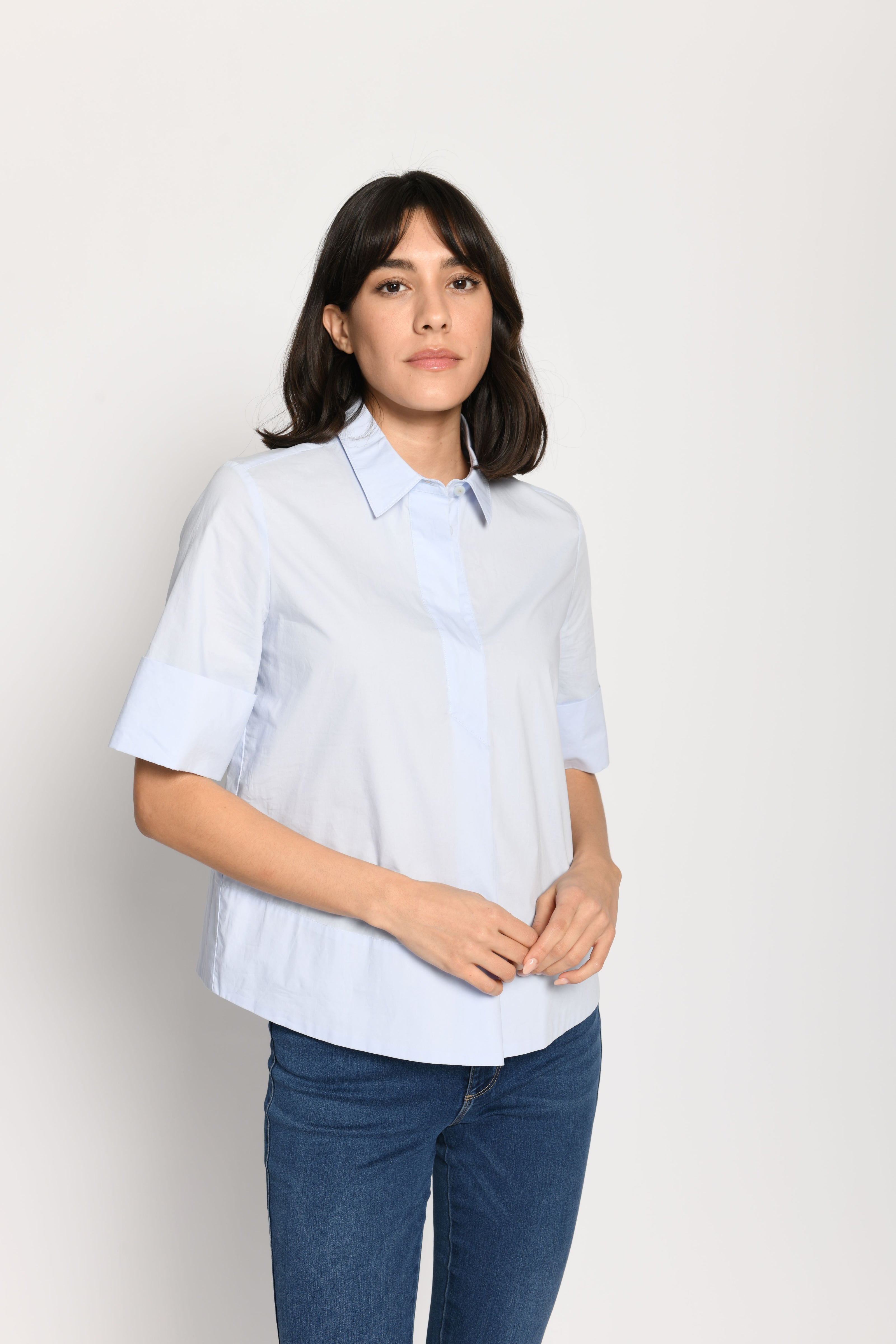 Model trägt kurze kastige Boxy-Bluse in der Farbe Hellblau mit kurzen Ärmeln, passend zu einer Jeans – Vorderansicht