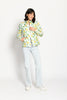 Model trägt leichte Steppjacke für Damen mit kräftigem Zitronen-Print auf weißer Jacke – stehende Pose, Blick nach vorne