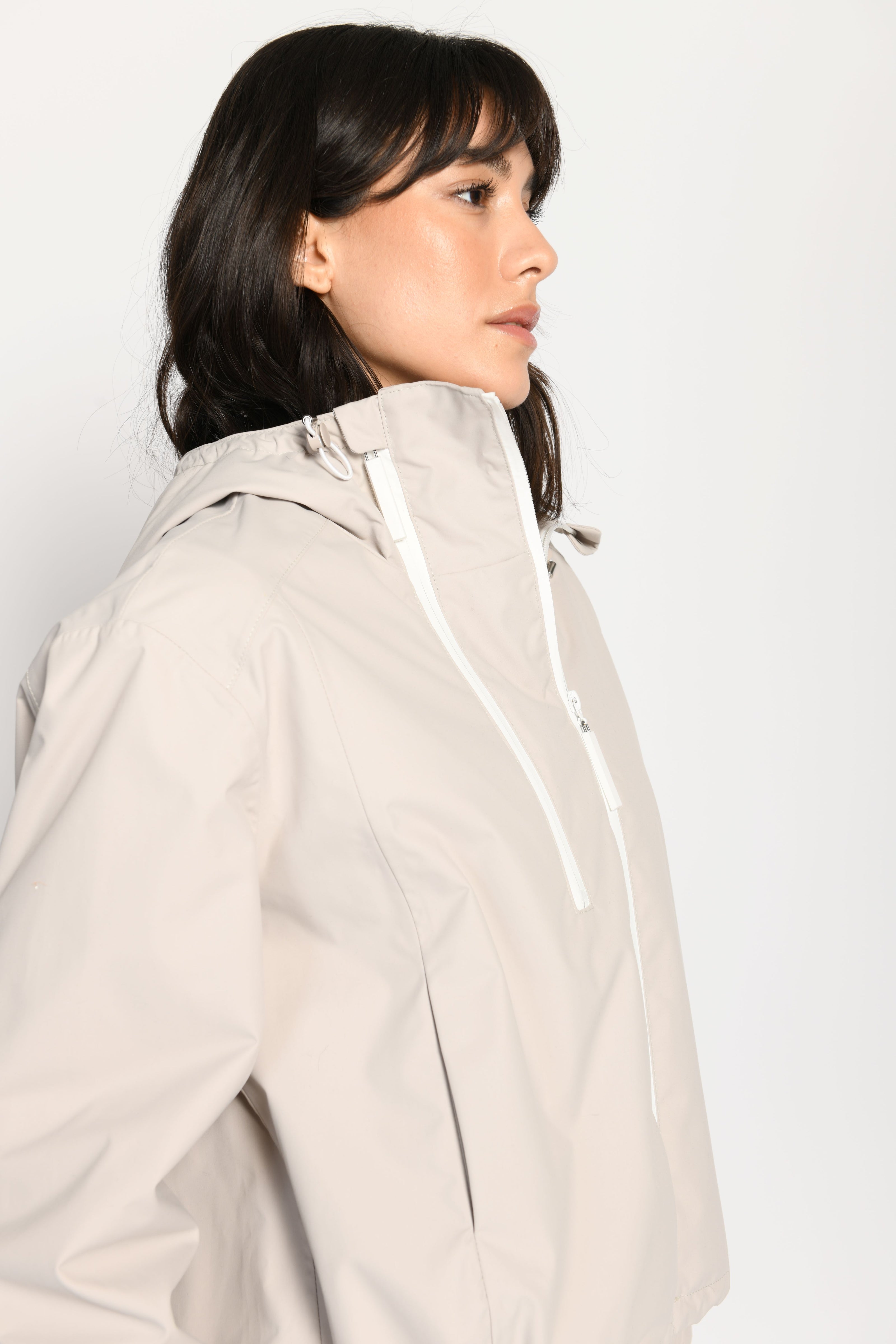 Beigefarbene kurze Outdoor-Kastenjacke mit zwei Reißverschlüssen und Kapuze – Nahaufnahme, Seitenansicht