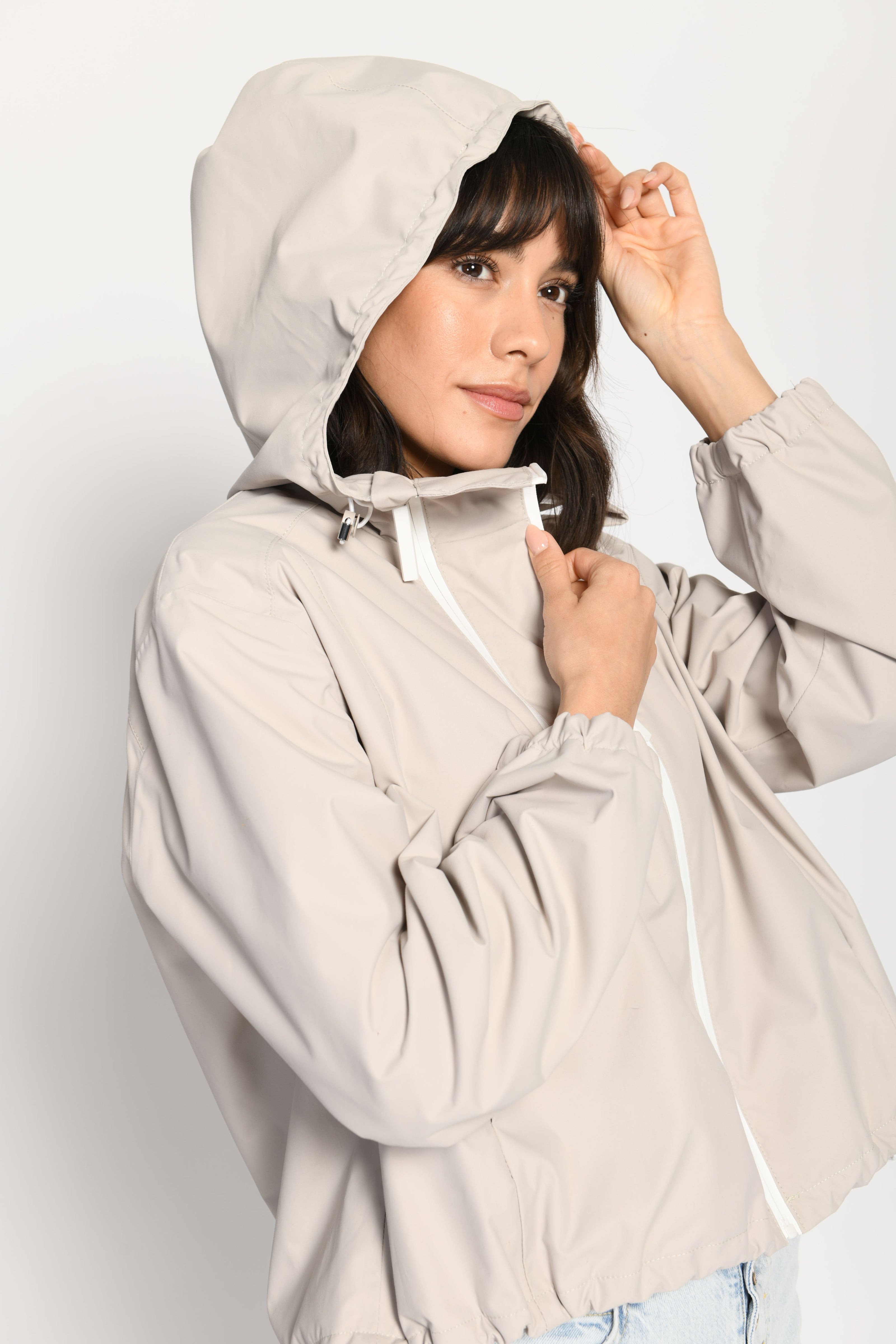 Beigefarbene kurze Outdoor-Kastenjacke mit zwei Reißverschlüssen und Kapuze – Seitenansicht von links