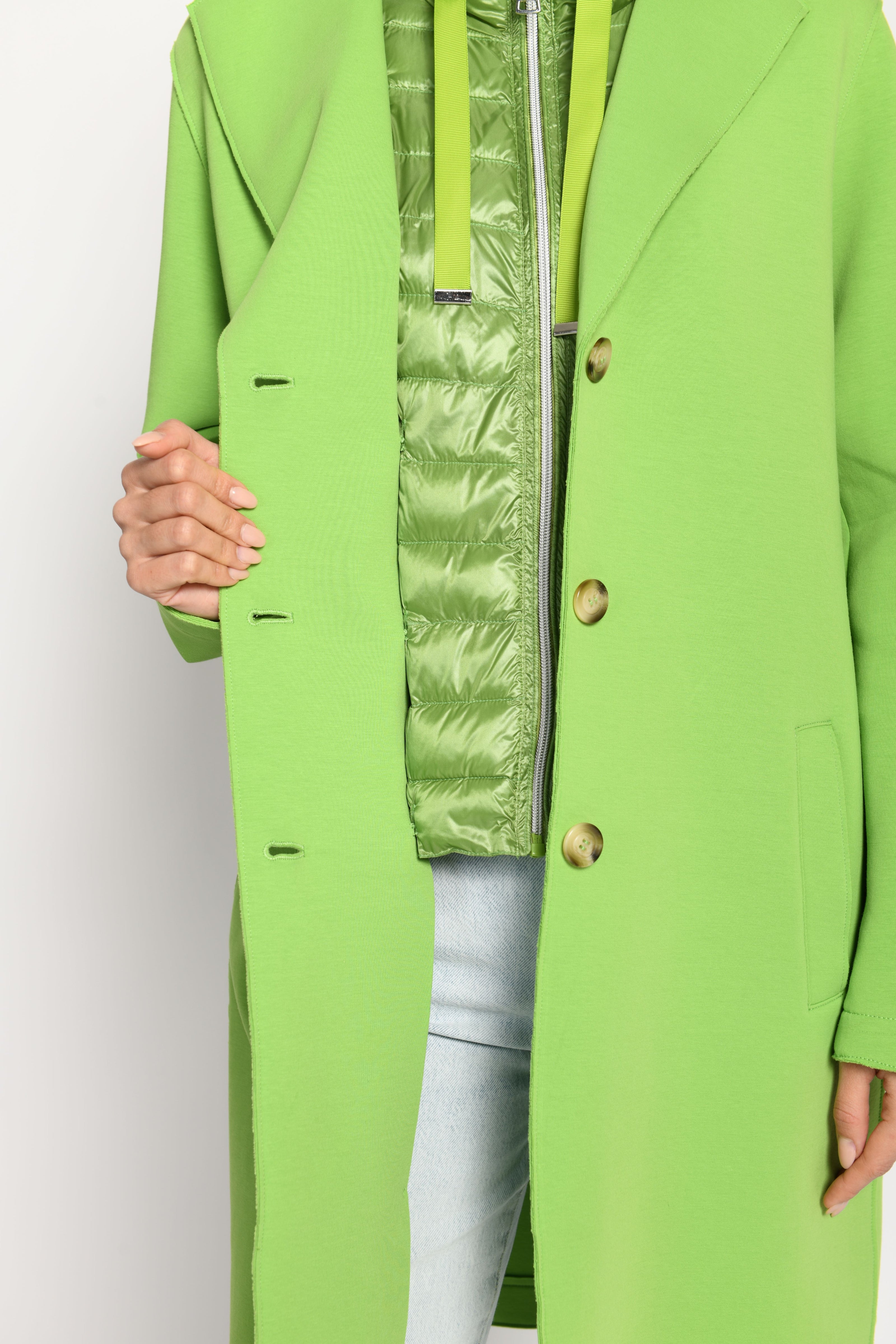 Detailaufnahme des sichtbaren grünen Westeneinsatzes inklusive Reißverschluss, Bänder und Knopfleiste – Vorderseite