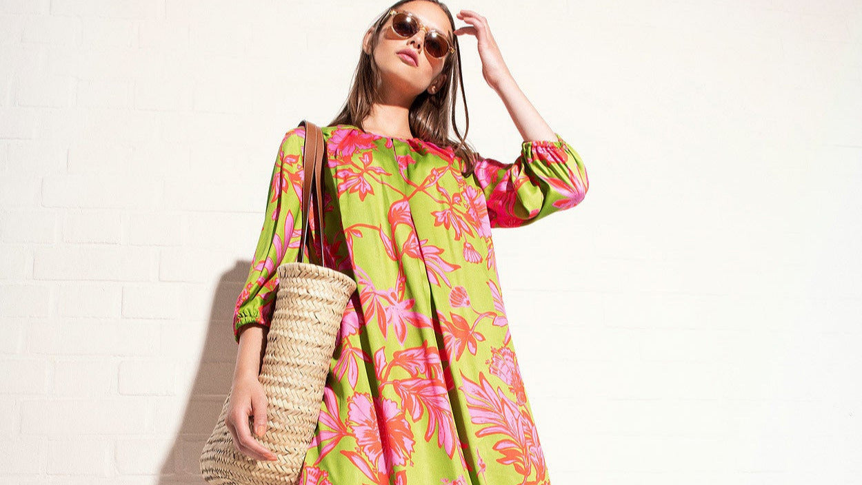 Model trägt grünes Kleid mit großen pinken floralen Prints aus leichter Viskose – Vorderansicht quer