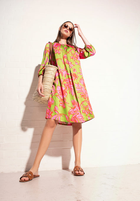 Model trägt grünes Kleid mit großen pinken floralen Prints aus leichter Viskose – Vorderansicht 