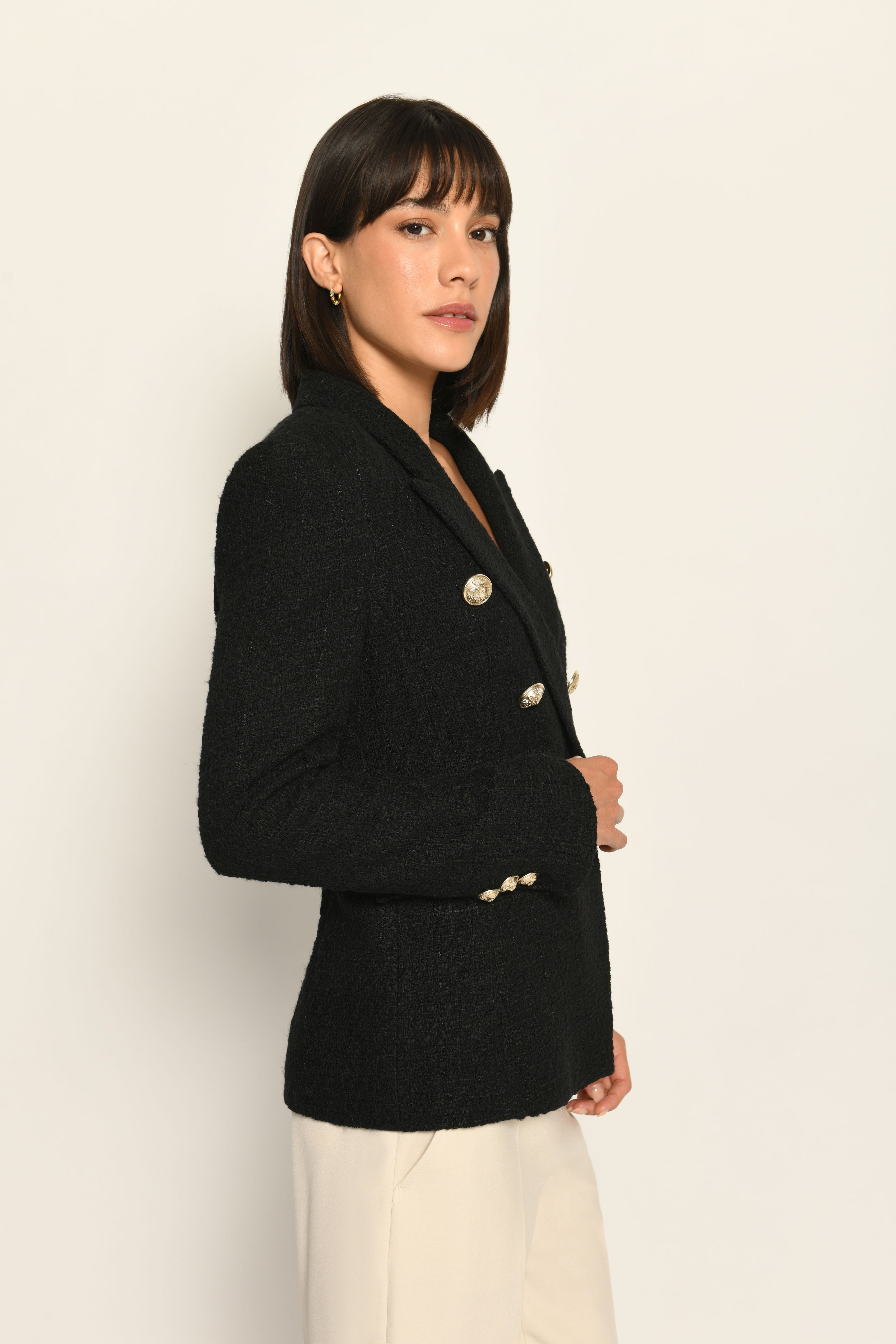 Zweireihiger schwarzer taillierter Bouclé-Blazer für Damen, kombiniert mit beiger Stoffhose – Seitenansicht