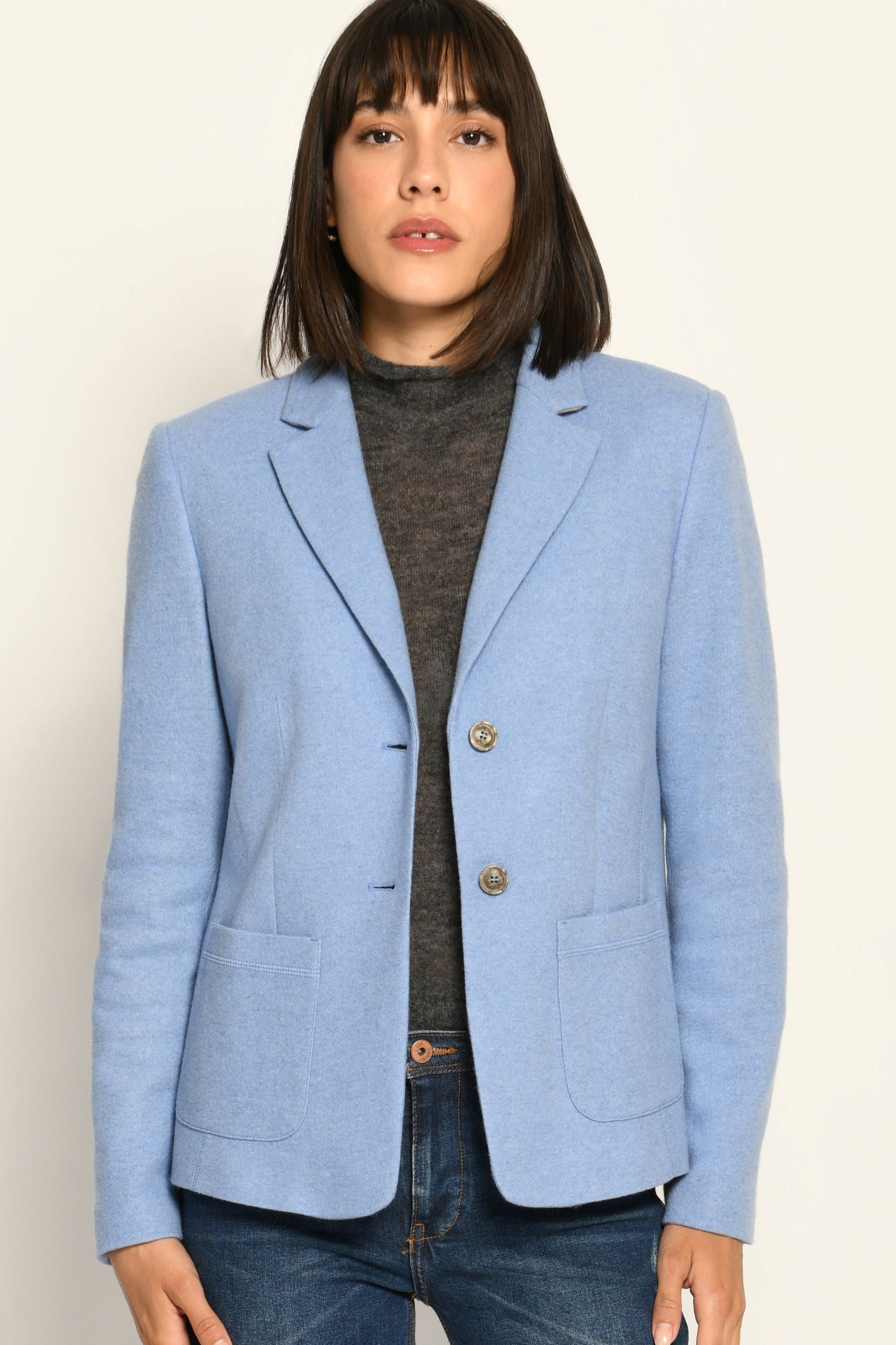 Klassisch designter Blazer für Damen in der Farbe Hellblau aus gestricktem Wollstoff, kombiniert zu Jeans – Nahaufnahme
