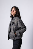 Model trägt Bouclé-Blouson für Damen in den Farben Schwarz und Weiß zu dunkler Stoffhose – Seitenansicht
