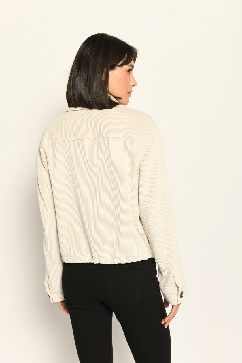 Cord-Blouson in der Farbe Creme mit großen Taschen und schwarzen Knöpfen, kombiniert zu schwarzer Hose – Rückansicht