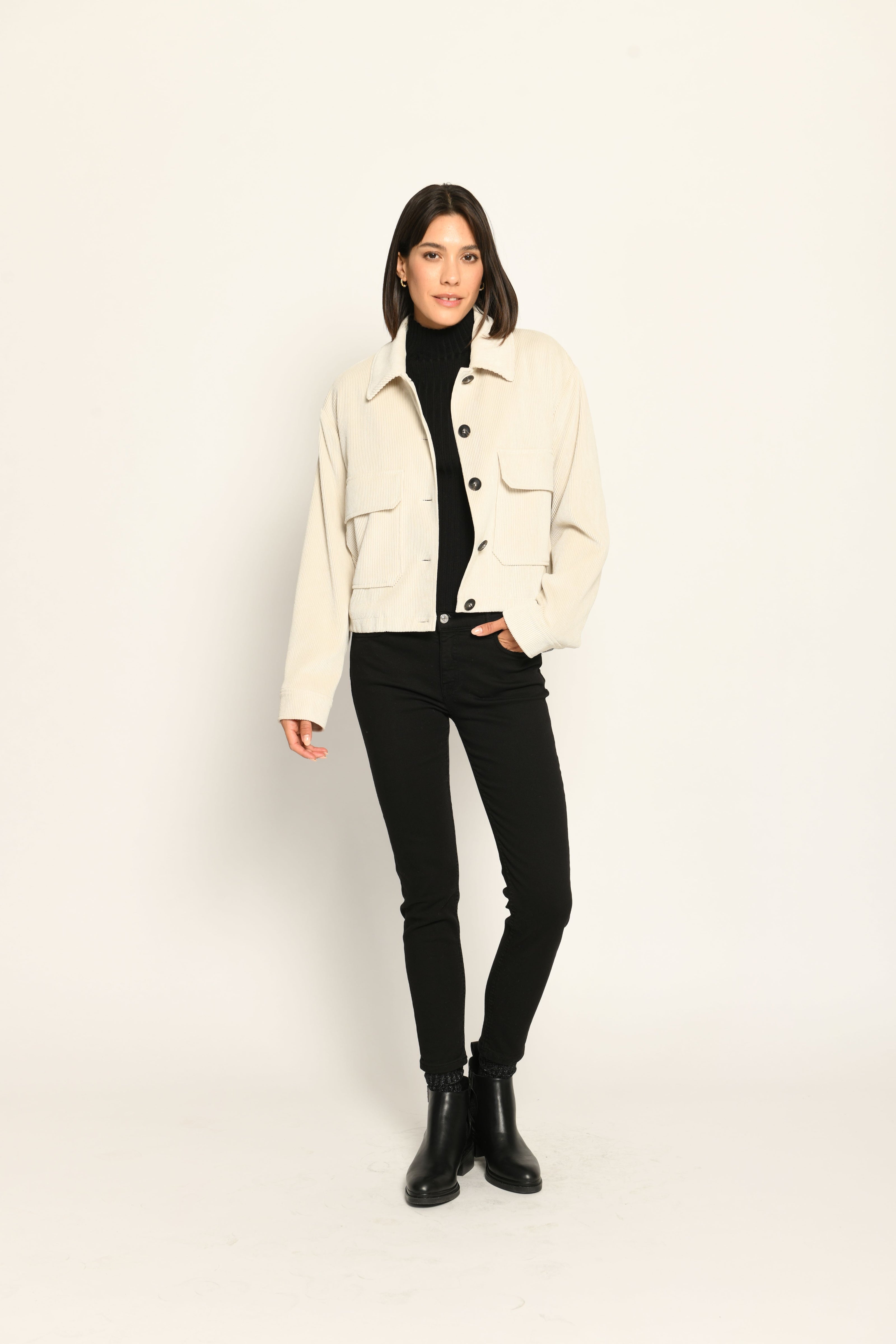 Cord-Blouson in der Farbe Creme mit großen Taschen und schwarzen Knöpfen, kombiniert zu schwarzer Hose – Vorderseite
