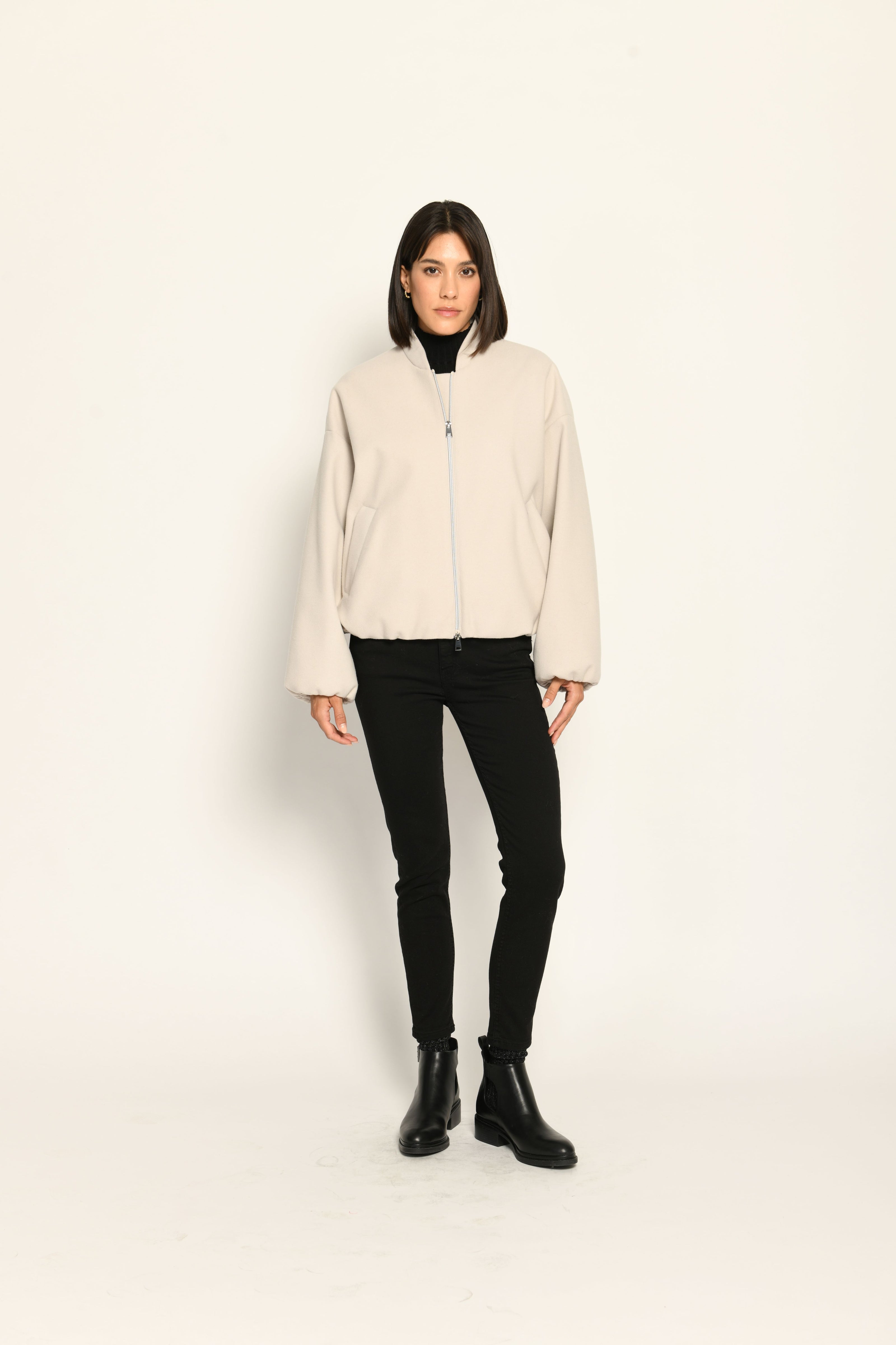 Model trägt oversized geschnittenen cremefarbenen Blouson für Damen zu schwarzer Jeans – Vorderseite