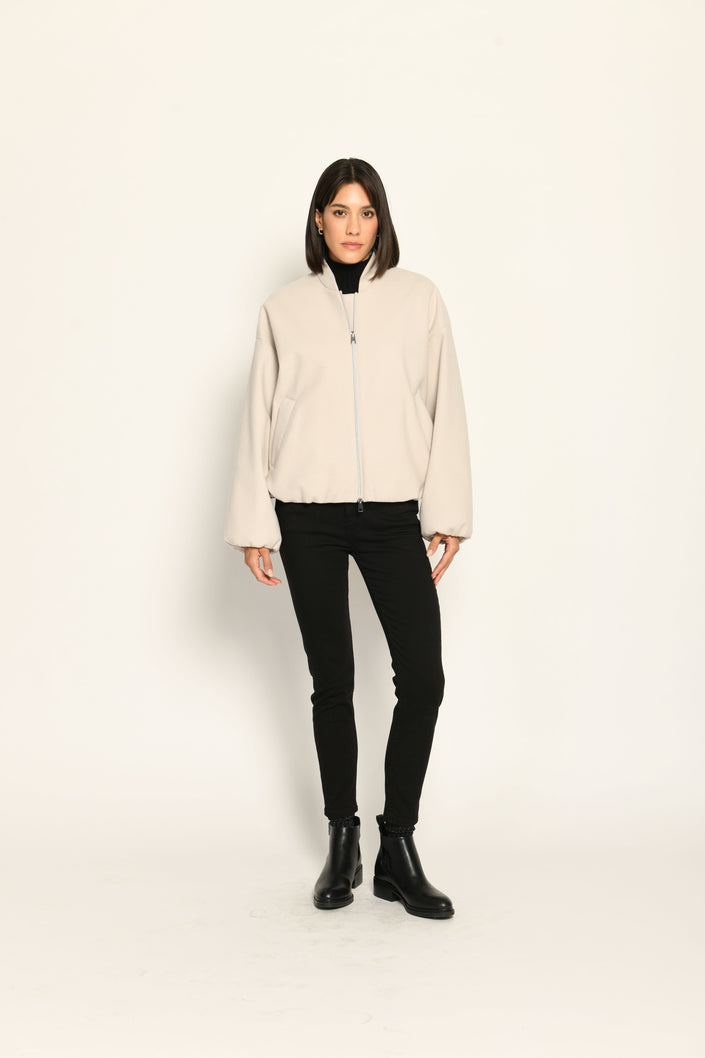 Model trägt oversized geschnittenen cremefarbenen Blouson für Damen zu schwarzer Jeans – Vorderseite