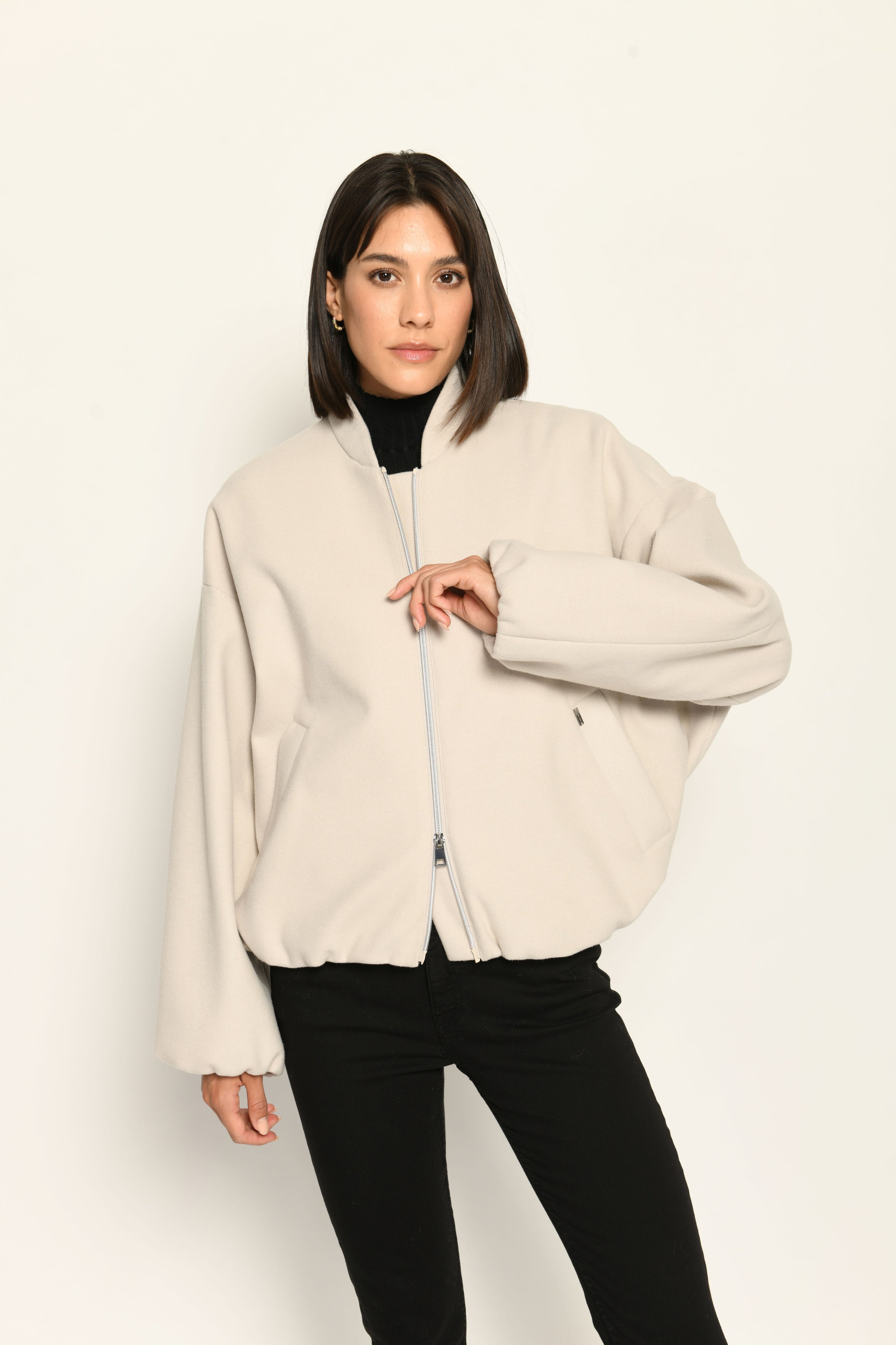 Model trägt oversized geschnittenen cremefarbenen Blouson für Damen zu schwarzer Jeans – Nahaufnahme Vorderseite