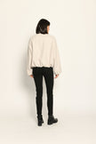 Model trägt oversized geschnittenen cremefarbenen Blouson für Damen zu schwarzer Jeans – Rückansicht 