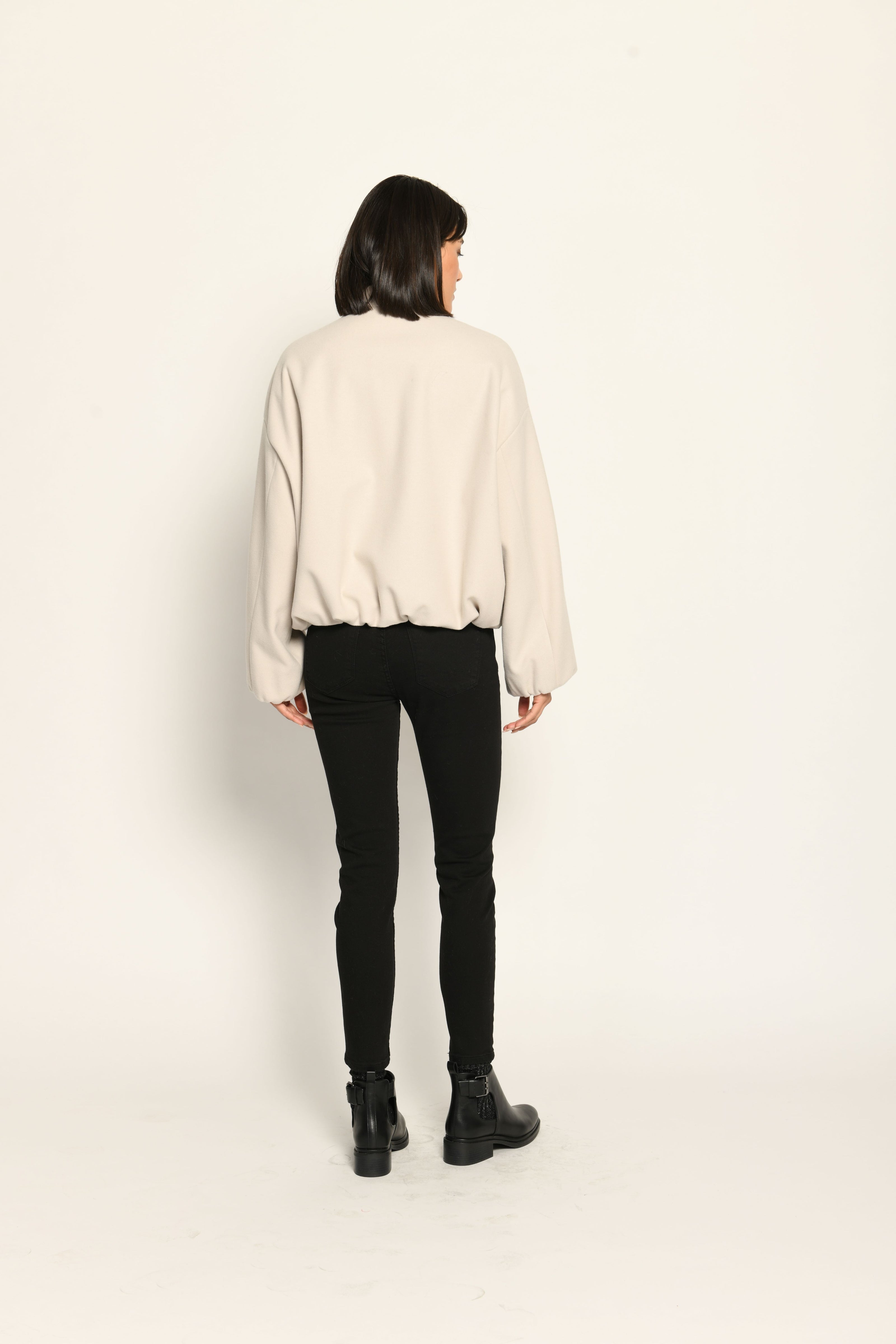 Model trägt oversized geschnittenen cremefarbenen Blouson für Damen zu schwarzer Jeans – Rückansicht 