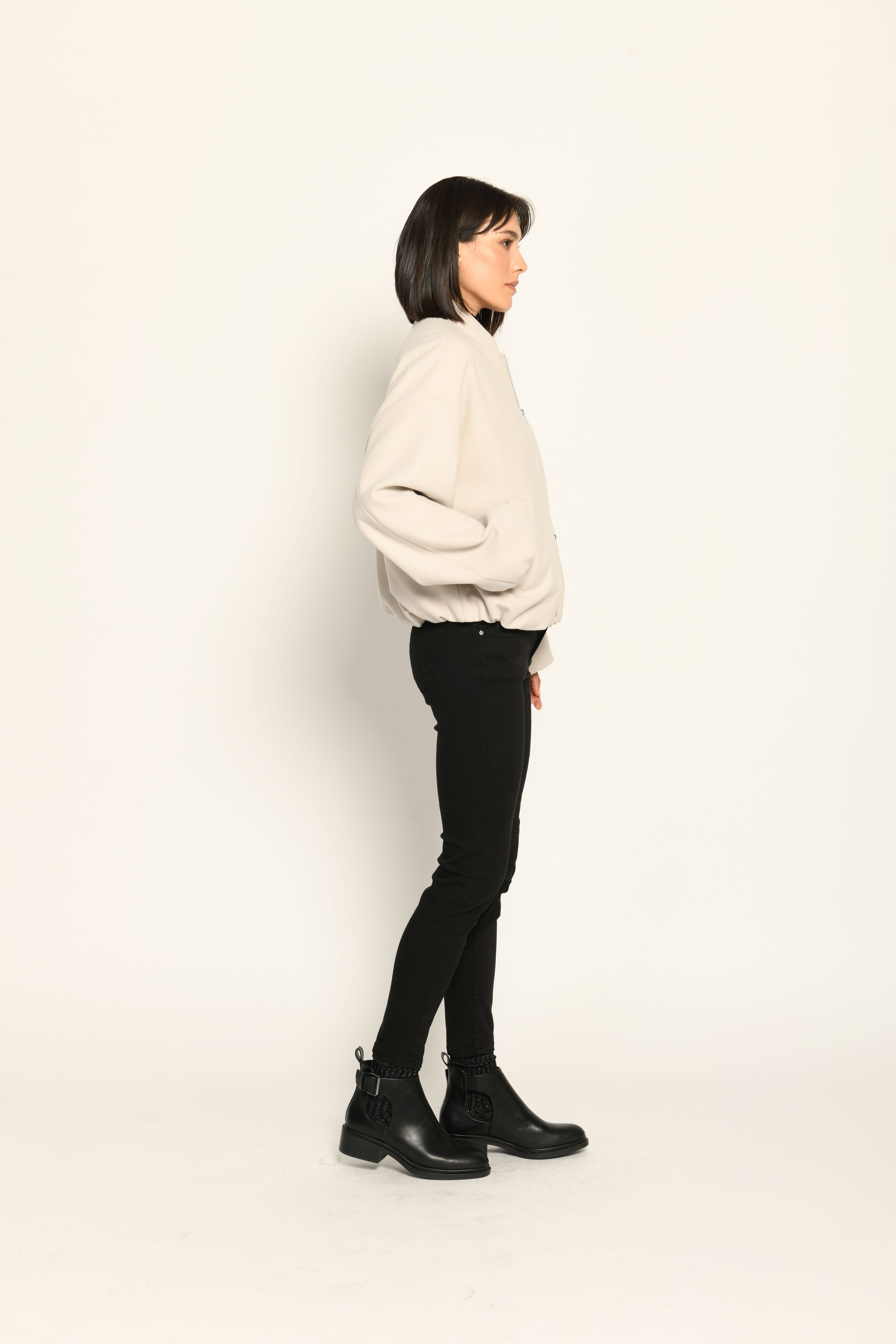 Model trägt oversized geschnittenen cremefarbenen Blouson für Damen zu schwarzer Jeans – Seitenansicht rechts