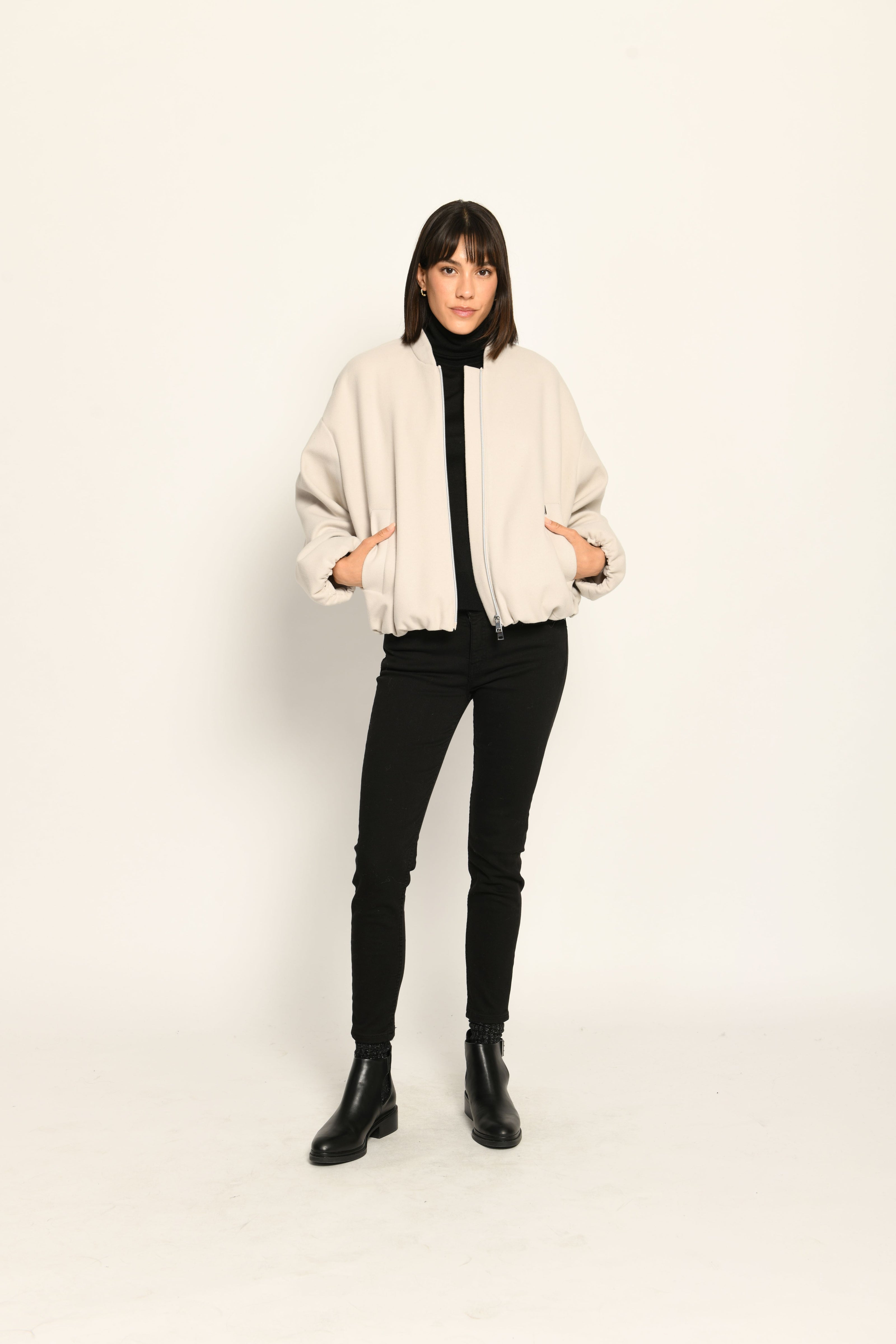 Model trägt oversized geschnittenen cremefarbenen Blouson für Damen zu schwarzer Jeans – Vorderansicht, offen