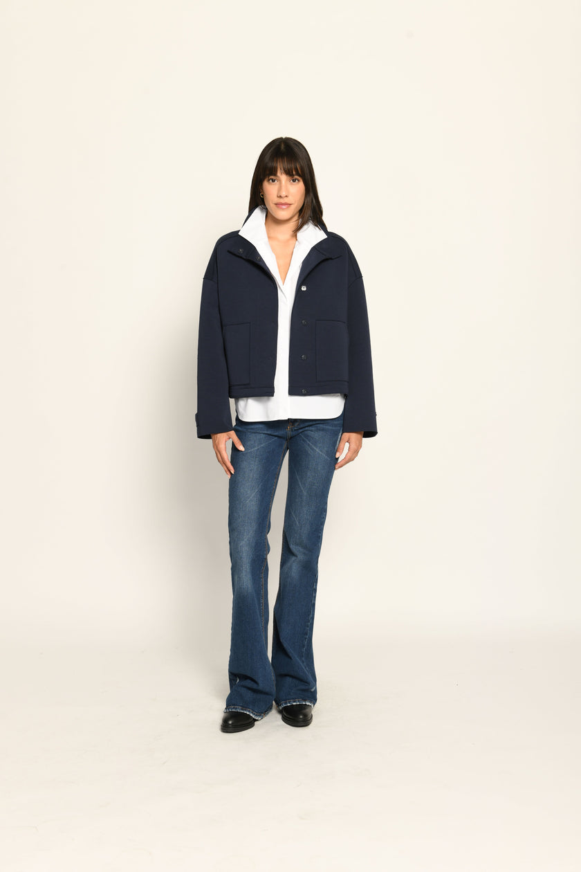 Model trägt dunkelblauen Blouson für Damen aus Scuba, lässig kombiniert zu einer weißen Bluse – Vorderansicht