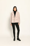 Beige Damenjacke im Caban-Stil mit Reverskragen und zweireihigem Knopfverschluss, kombiniert zu schwarzer Hose.