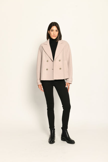 Beige Damenjacke im Caban-Stil mit Reverskragen und zweireihigem Knopfverschluss, kombiniert zu schwarzer Hose.
