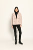 Beige Damenjacke im Caban-Stil mit Reverskragen und zweireihigem Knopfverschluss, kombiniert zu schwarzer Hose.