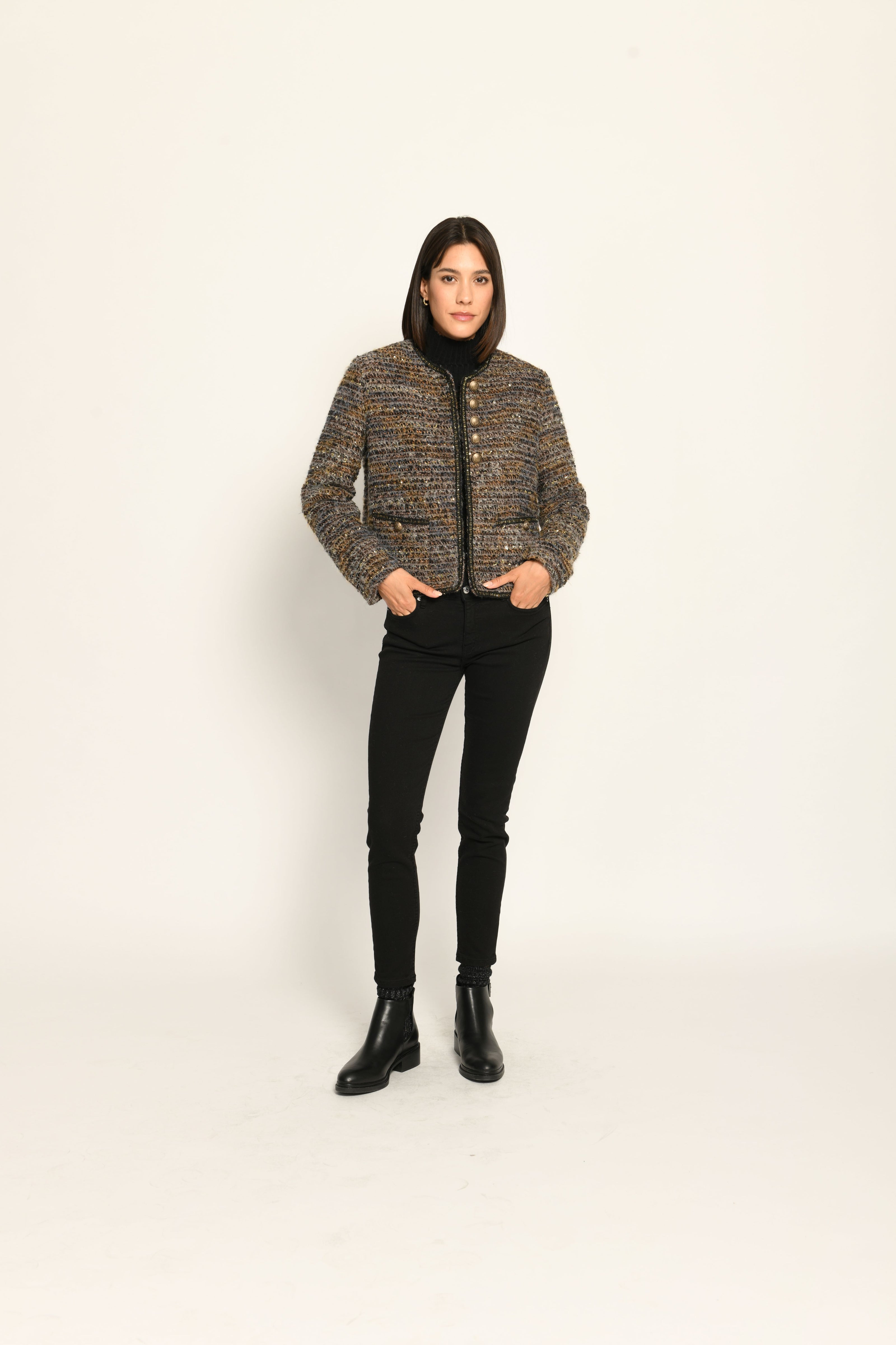 Model trägt Kurzjacke aus Bouclégewebe mit Glanzgarn und Schmuckborte zu einer schwarzen Jeans – stehende Pose