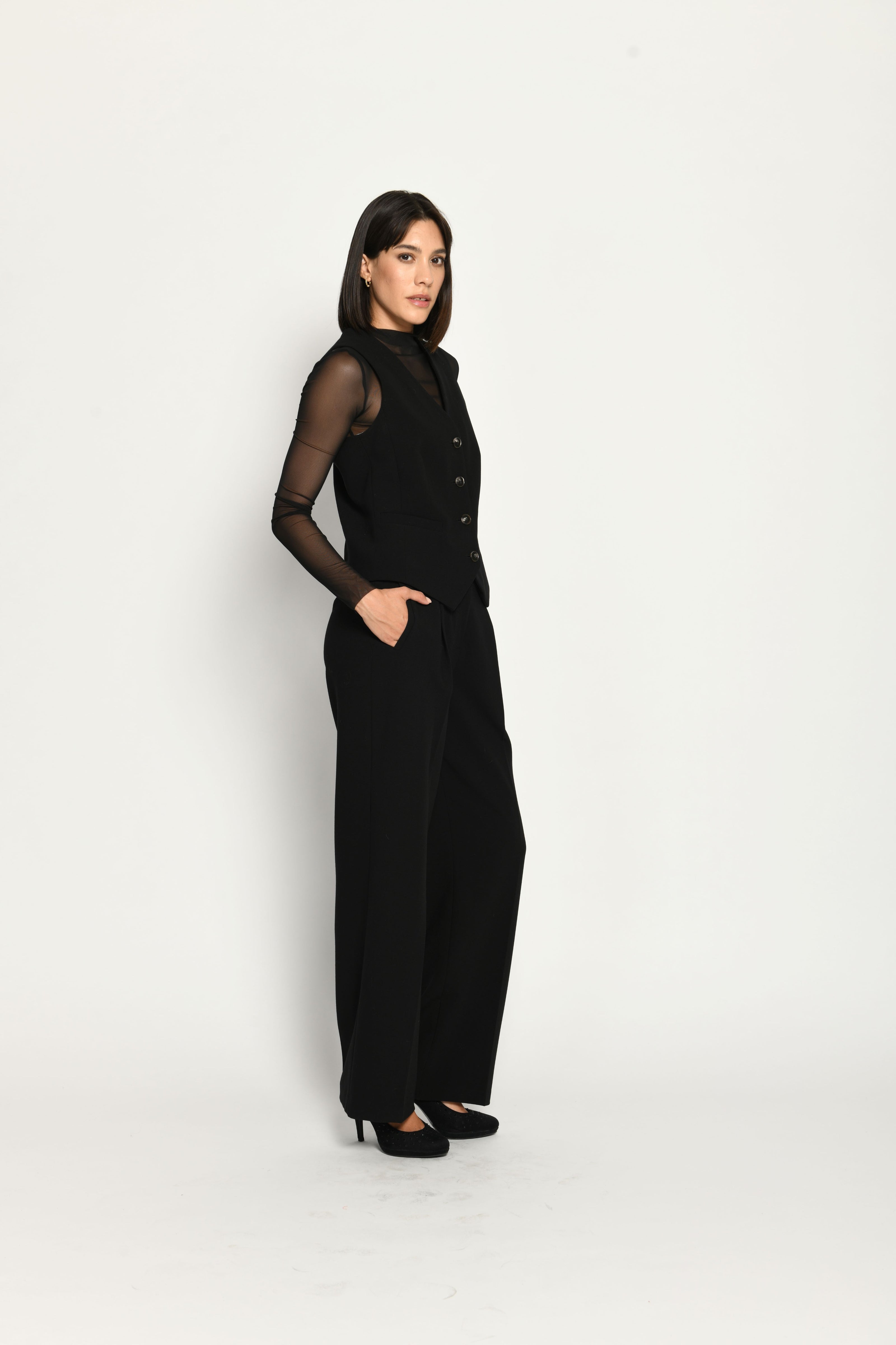 Schwarzer Slim-Fit-Hosenanzug für Damen. Model trägt Weste und lange Stoffhose – rechte Seitenansicht.