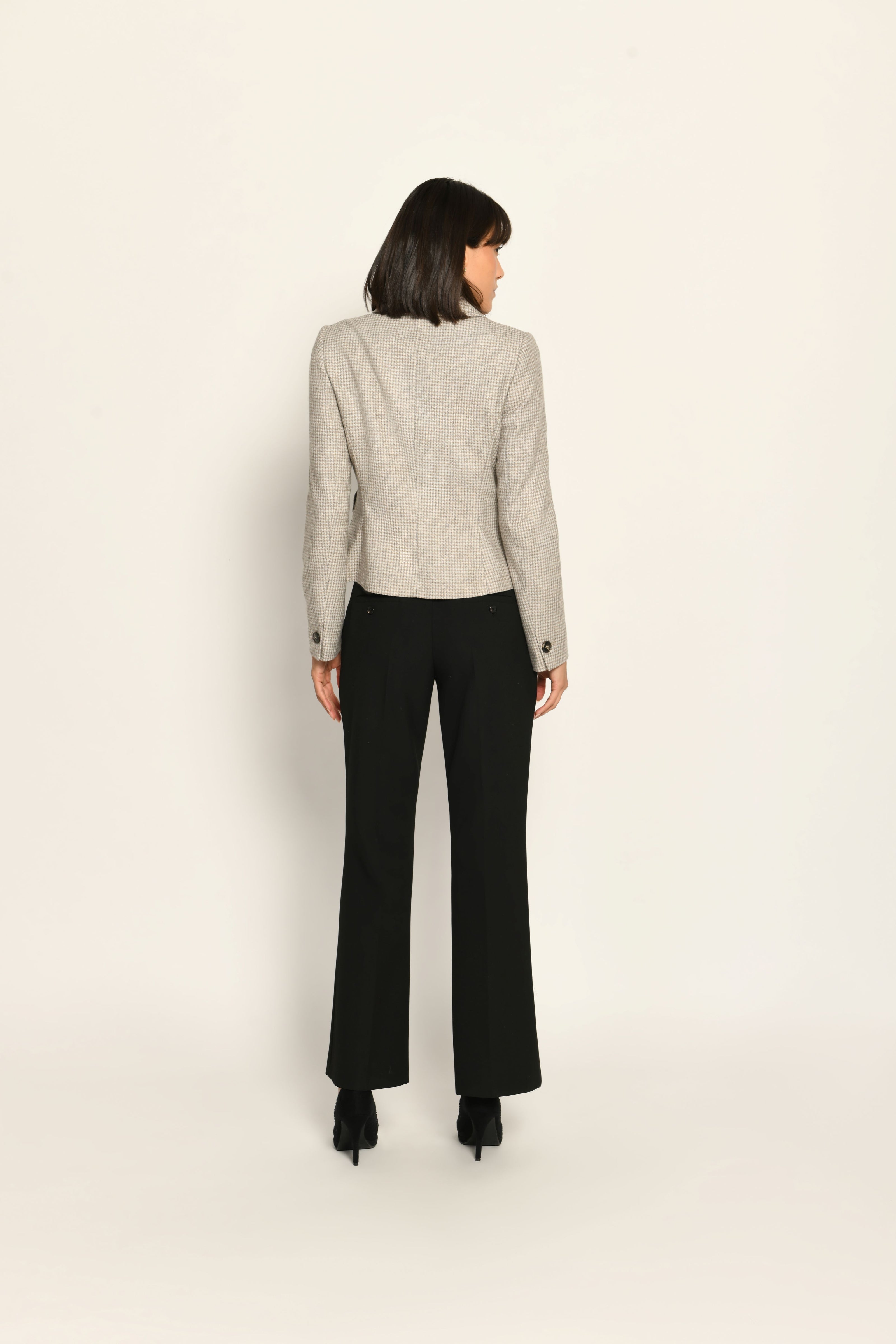 Kurze Slim-Fit-Jacke mit Pepitamuster für Damen, kombiniert mit schwarzer Stoffhose – Rückansicht