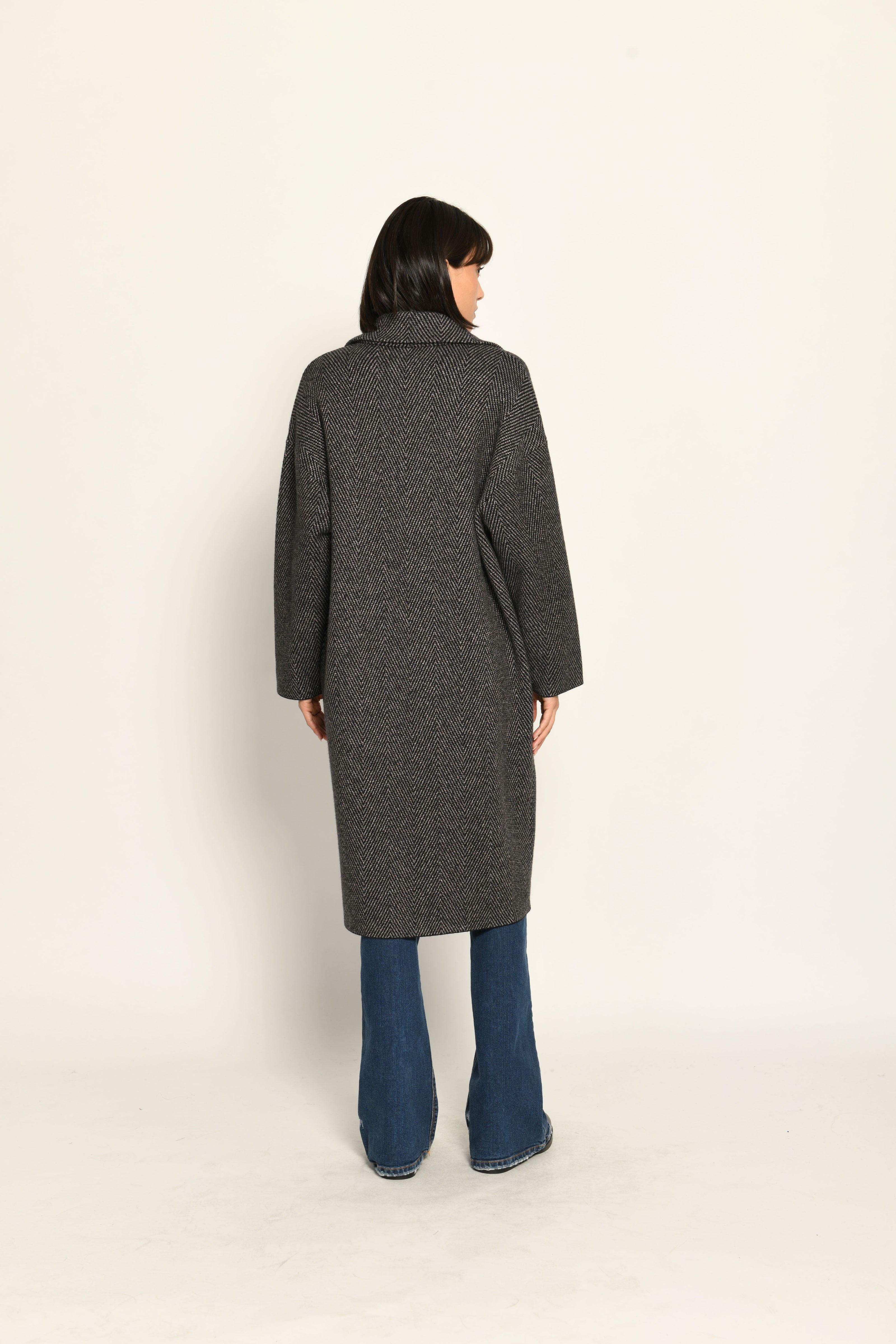 Lässiger Oversize-Strickmantel mit überschnittenen Schultern und Reverskragen, kombiniert zu Jeans – Rückansicht