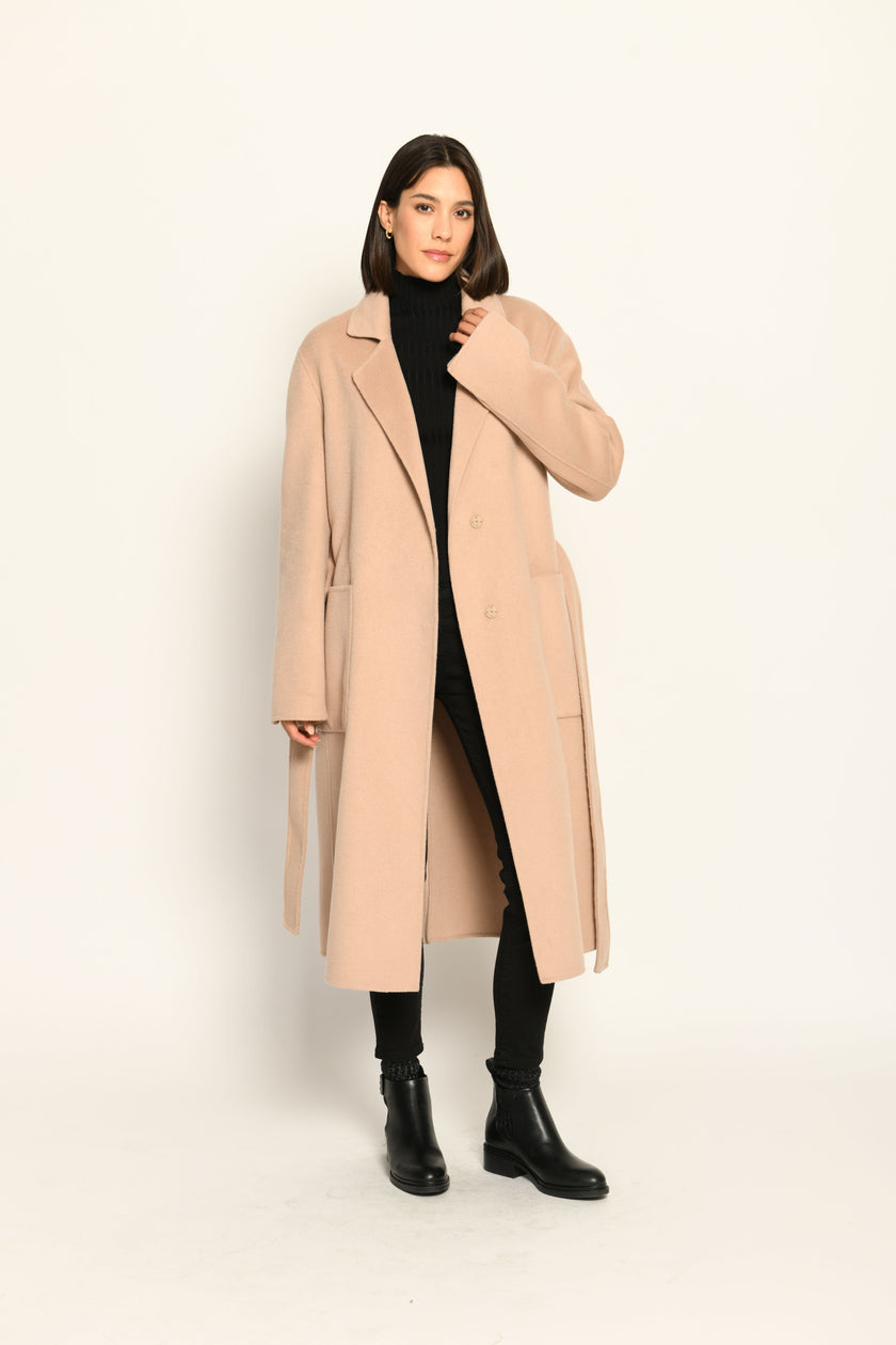 Langer Mantel für Damen in der Farbe Camel mit Reverskragen, Bindegürtel und aufgesetzten Taschen – offen getragen.