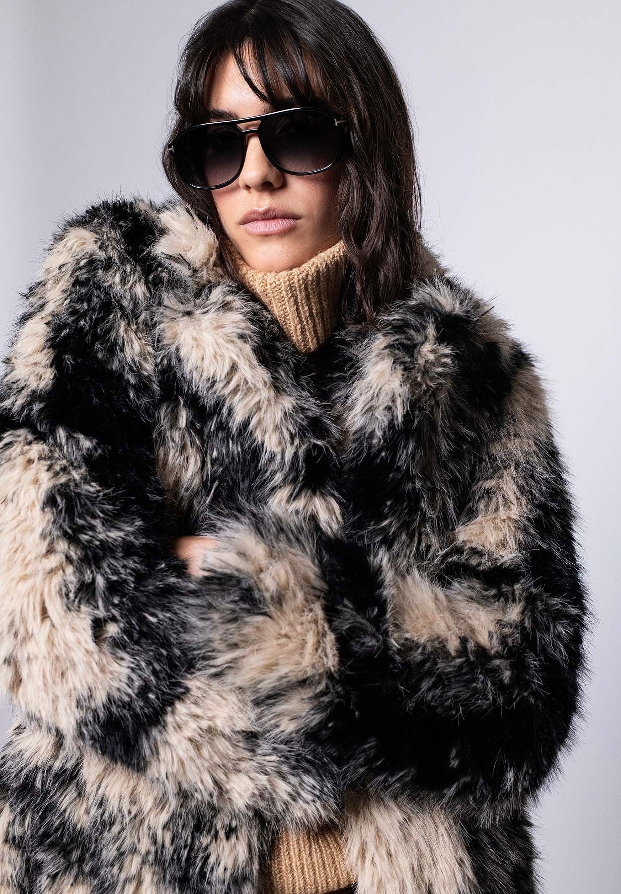 Damenmantel aus langhaarigem schwarz-beigen Webpelz für den Winter – Vorderansicht, geschlossen getragen