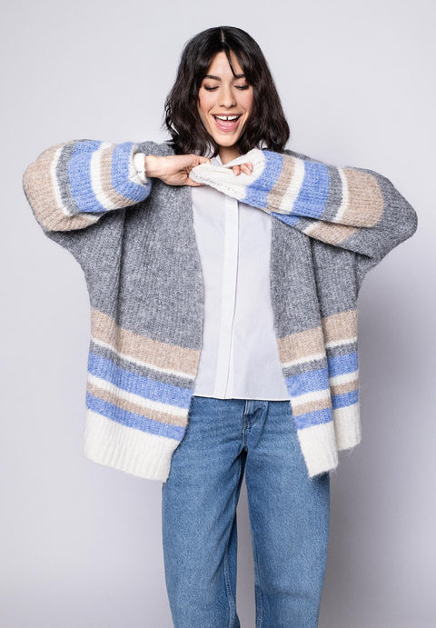 Offene graue Strickjacke für Damen mit beigen, blauen und cremefarbenen Querstreifen, kombiniert mit weißer Bluse.