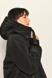 Model trägt schwarze gefütterte Wendejacke aus wärmendem Teddy-Webpelz mit Kapuze – Nahaufnahme Nylon-Außenseite