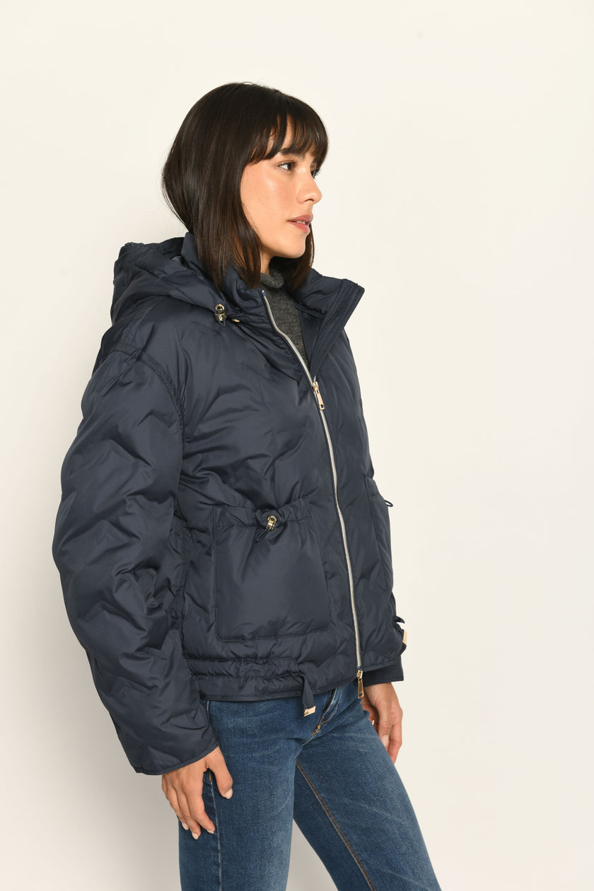 Model trägt sportive dunkelblaue Steppjacke für Damen mit Kapuze zu dunkelblauer Jeans – Nahaufnahme Seitenansicht