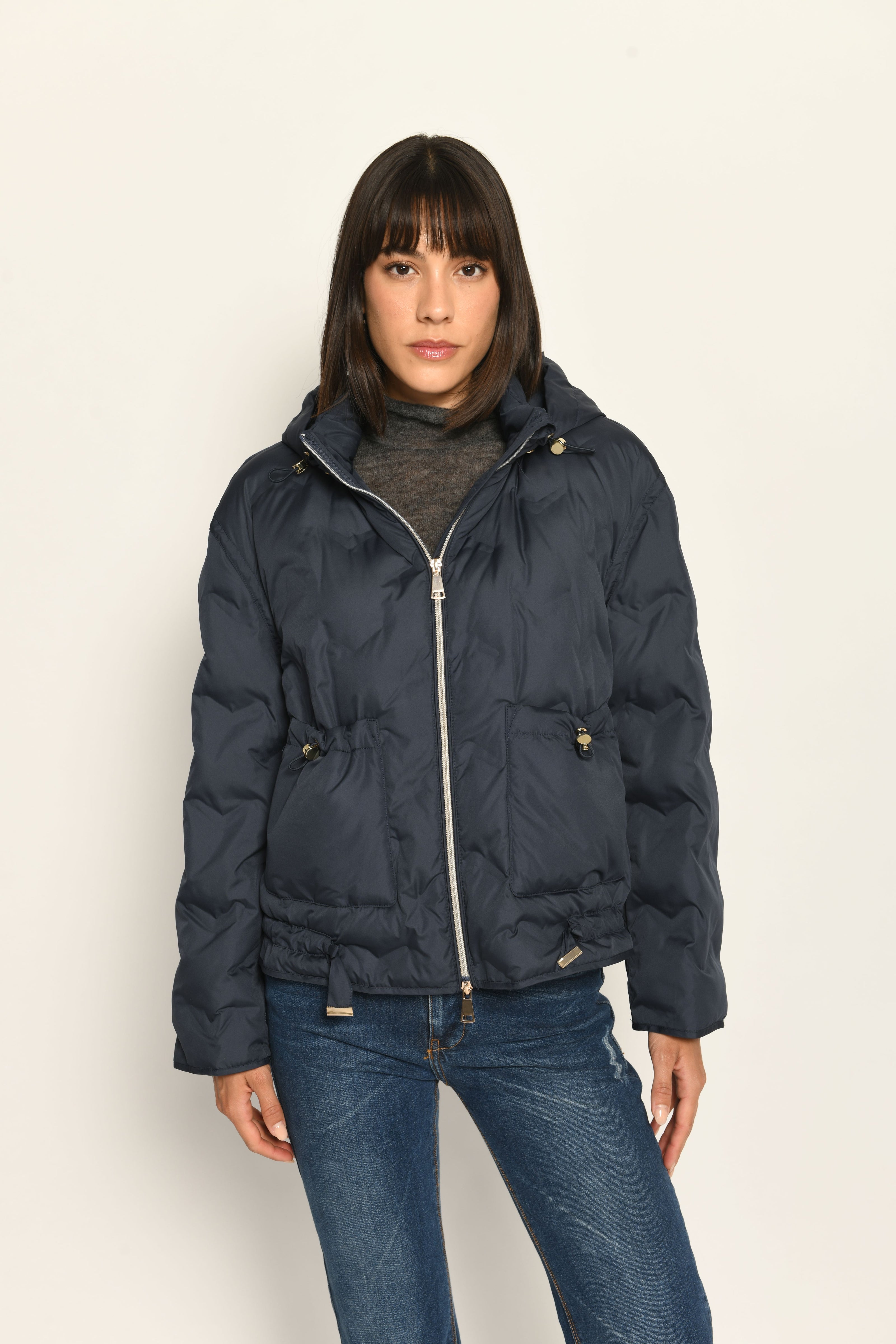 Model trägt sportive dunkelblaue Steppjacke für Damen mit Kapuze zu dunkelblauer Jeans – Nahaufnahme Vorderseite