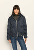Model trägt sportive dunkelblaue Steppjacke für Damen mit Kapuze zu dunkelblauer Jeans – Nahaufnahme Vorderseite