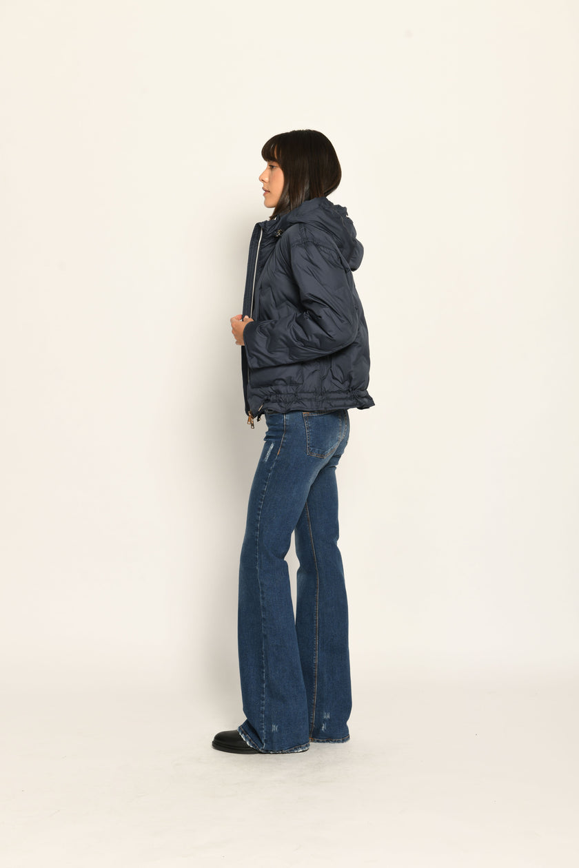 Model trägt sportive dunkelblaue Steppjacke für Damen mit Kapuze zu dunkelblauer Jeans – Seitenansicht links