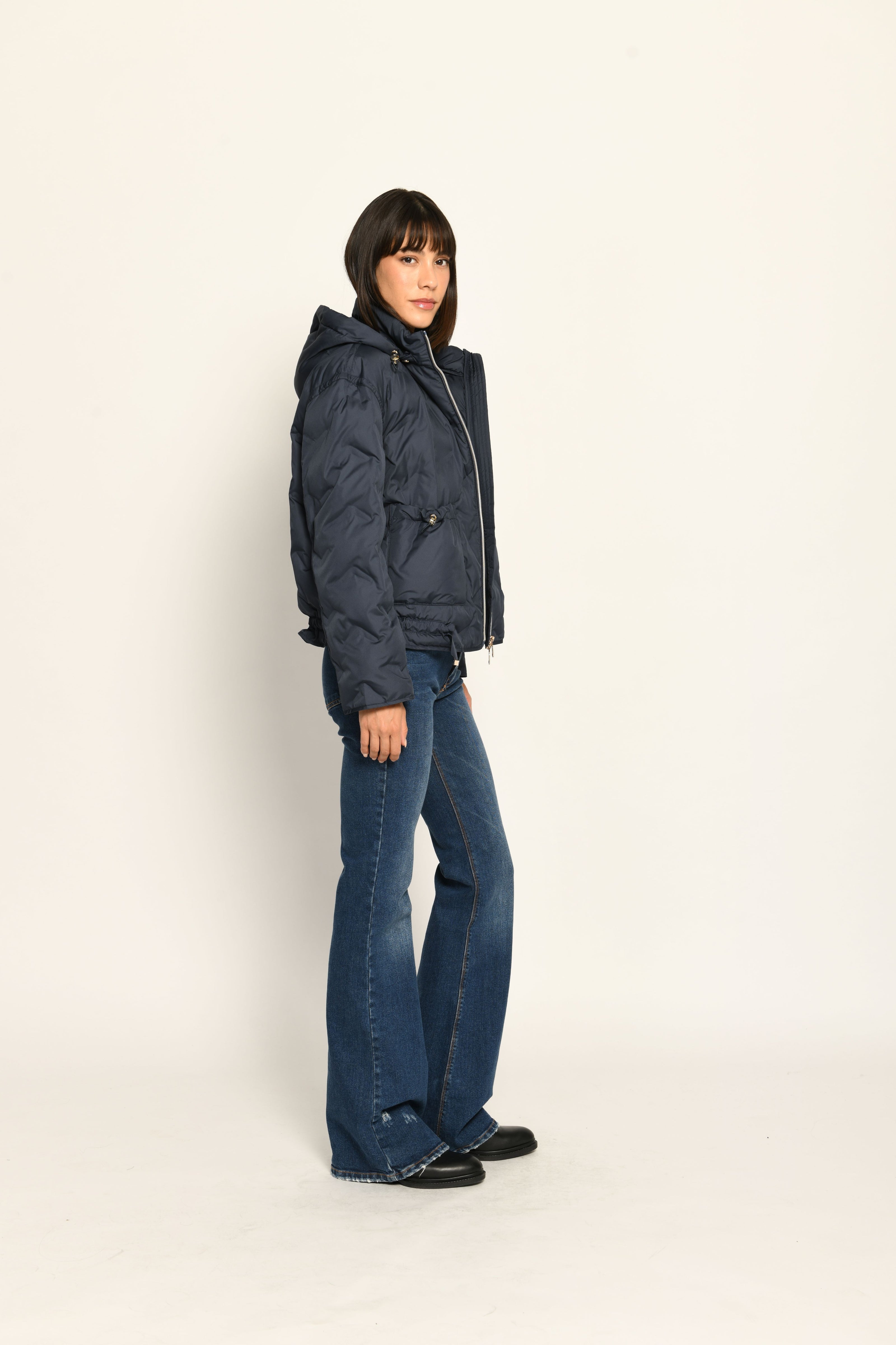 Model trägt sportive dunkelblaue Steppjacke für Damen mit Kapuze zu dunkelblauer Jeans – Seitenansicht rechts