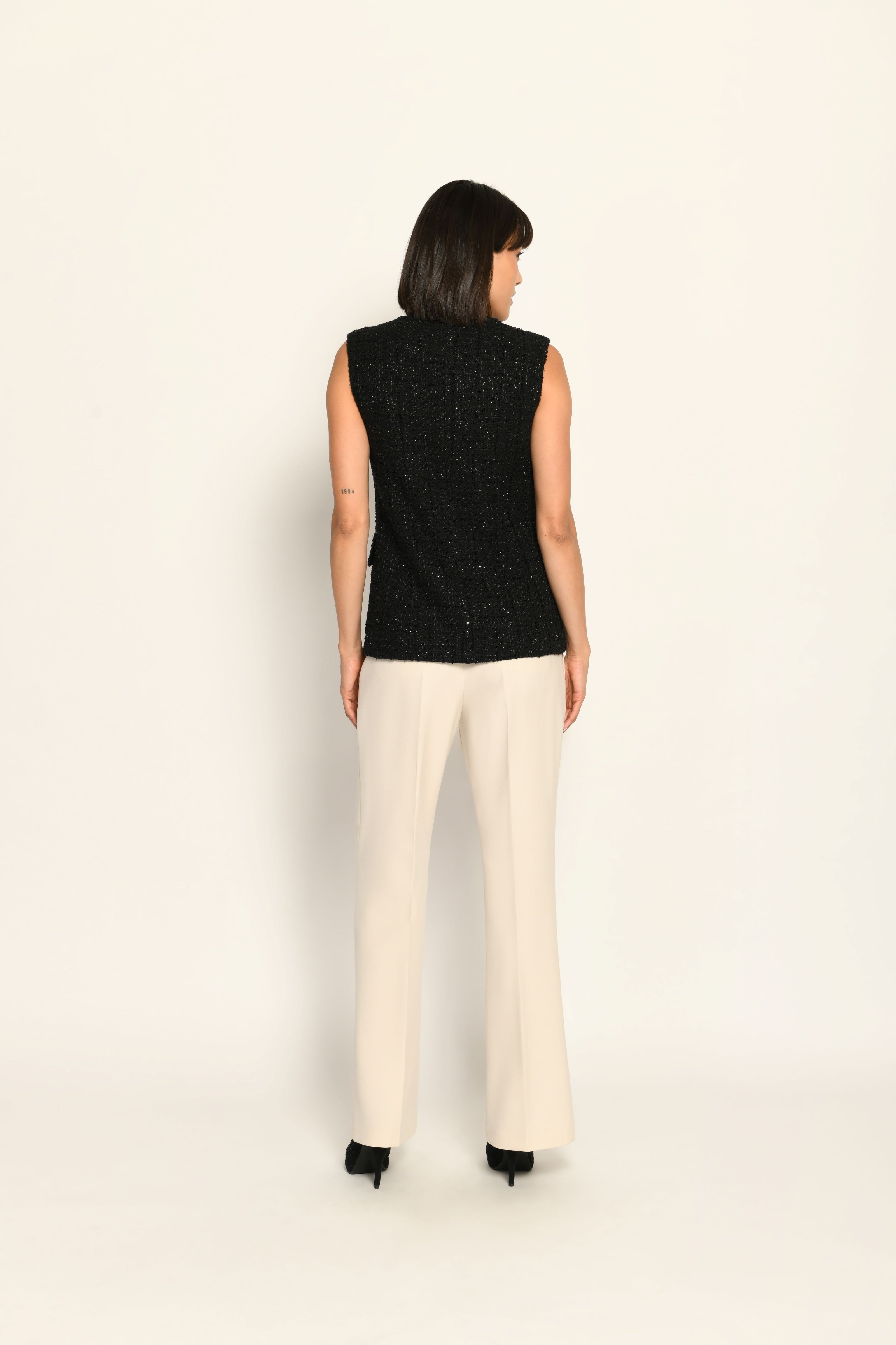 Schwarze taillierte Bouclé-Weste mit edlen Pailletten für Damen, kombiniert mit beiger Stoffhose – Rückansicht